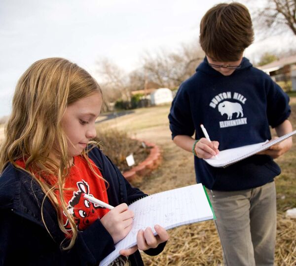 Two students writing in notebook outdoors