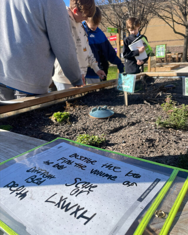 Plant chart and student inspecting garden box